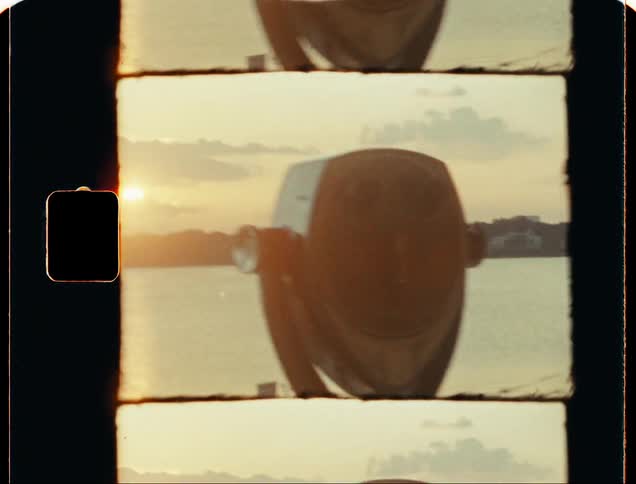 Coin operated beach binoculars in front of the shoreline at sunset caught on vintage film