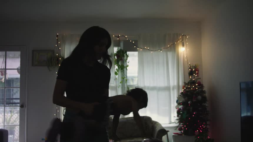 A mother playing with her baby and spinning them in the air at home