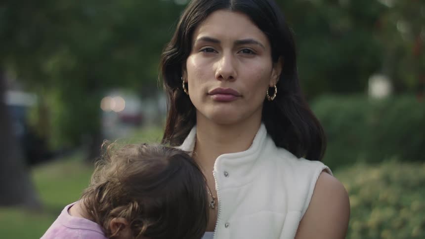 A mother is holding her baby outdoors in spring