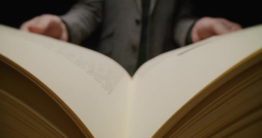 A man dramatically closes a religious book on a table