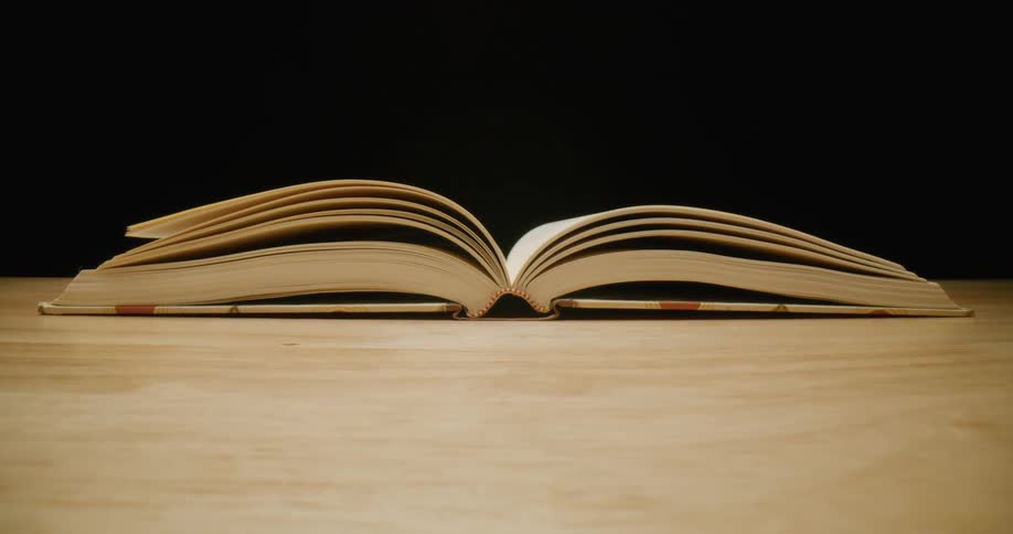 An open hardback book on a wooden table