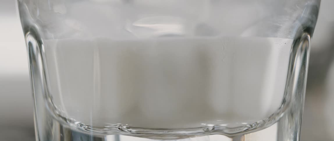 Close-up view of a glass being filled with milk at a cafe