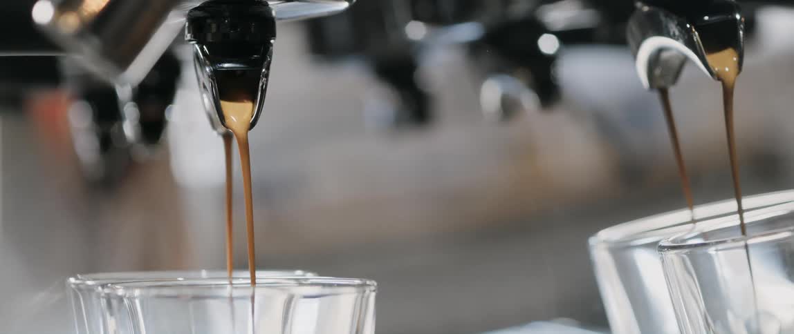 Frothy espresso is brewed and pouring into glasses
