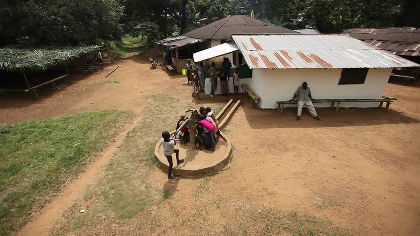 Children standing around a well connected to some homes