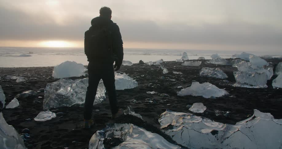 A man is walking on the coast of a beach in winter