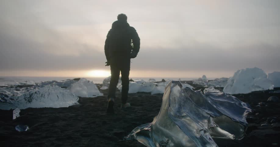 A man is walking on the beach in winter at dusk