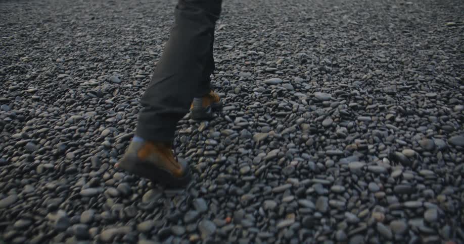 A person in hiking boots walking over rocky ground