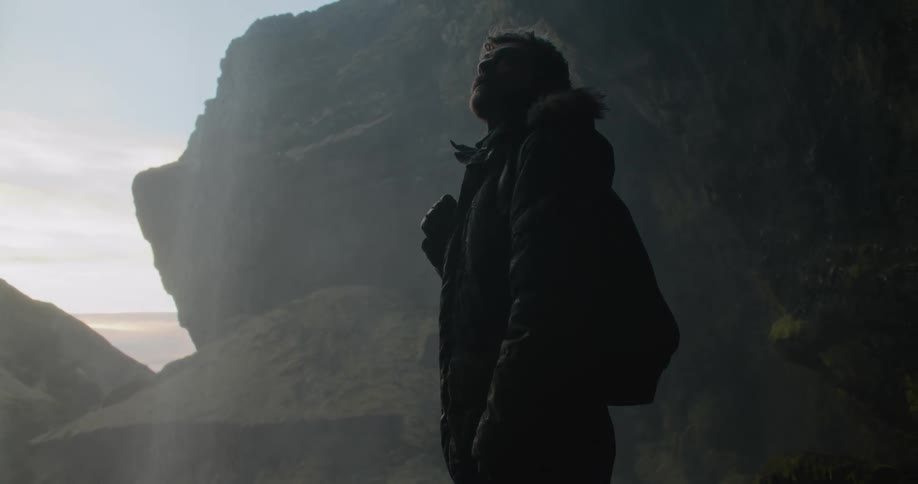 A man watches a waterfall crashing over a cliff