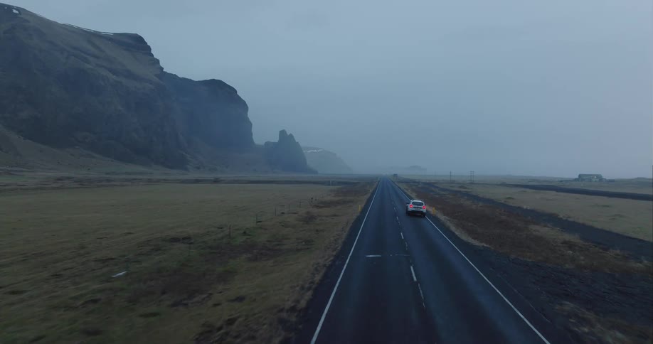 A car is driving on a highway in a rural area