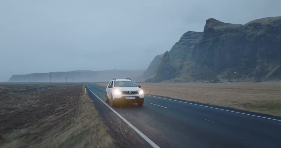 Cars are driving on a road in a rural area