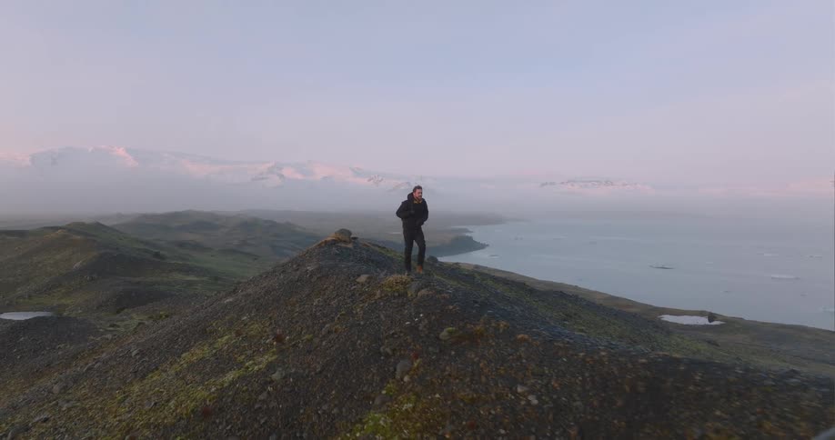 A man is walking on the hills near the shore