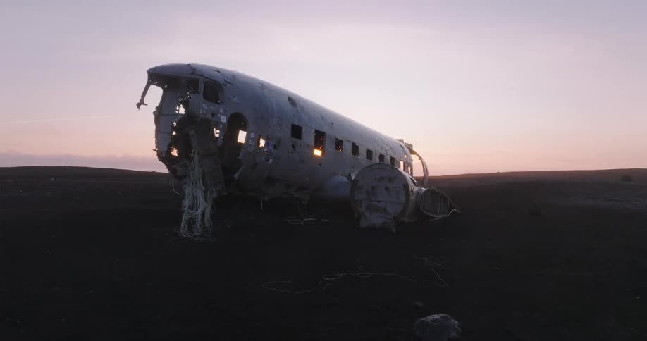 Airplane wreckage on an open field with two people in the far distance