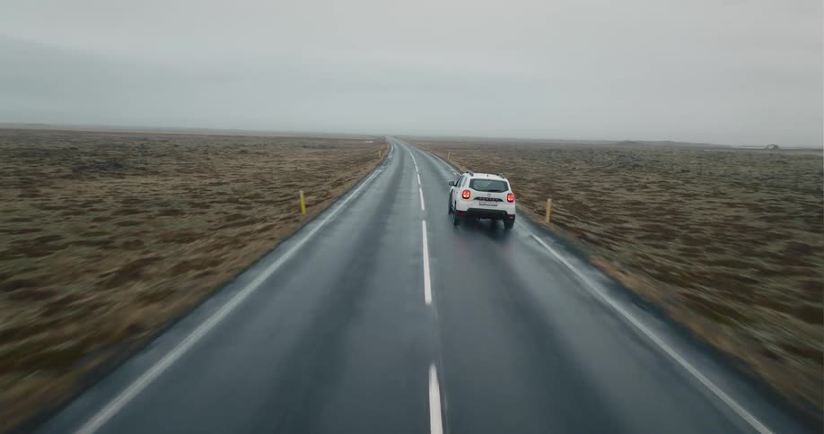 A car is driving on a highway in a rural area