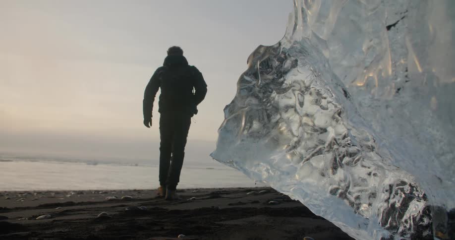 A photographer walks past a melting iceberg