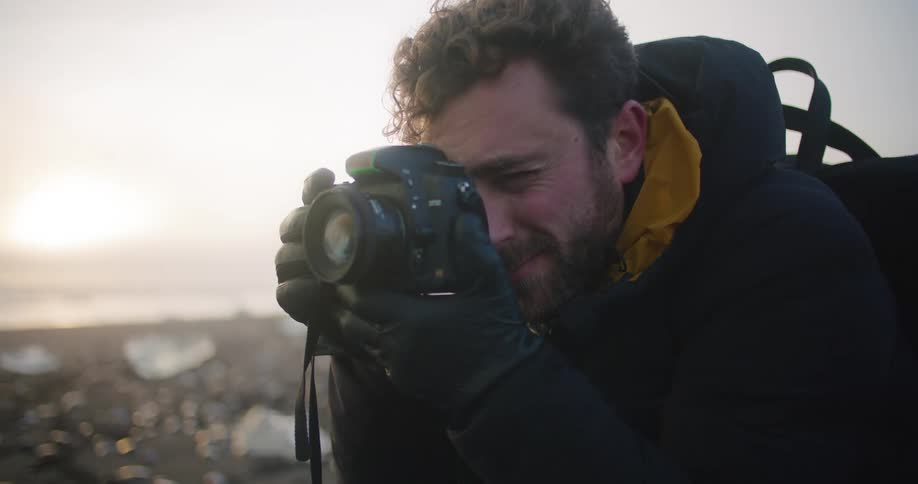 A man is taking photographs by the water