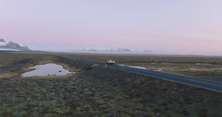 A car is driving on an empty road on the counrtryside