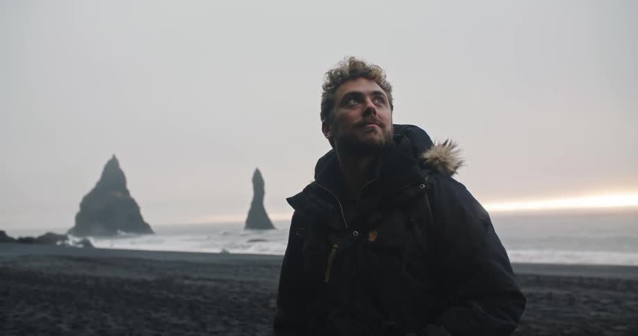 A man is wearing a coat at the beach in winter