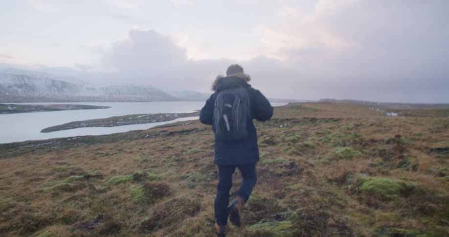 A man is hiking outdoors while the sun is setting
