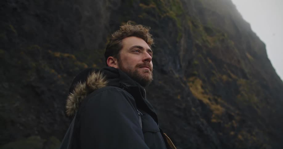A man in a heavy coat hiking in nature on a windy cold day