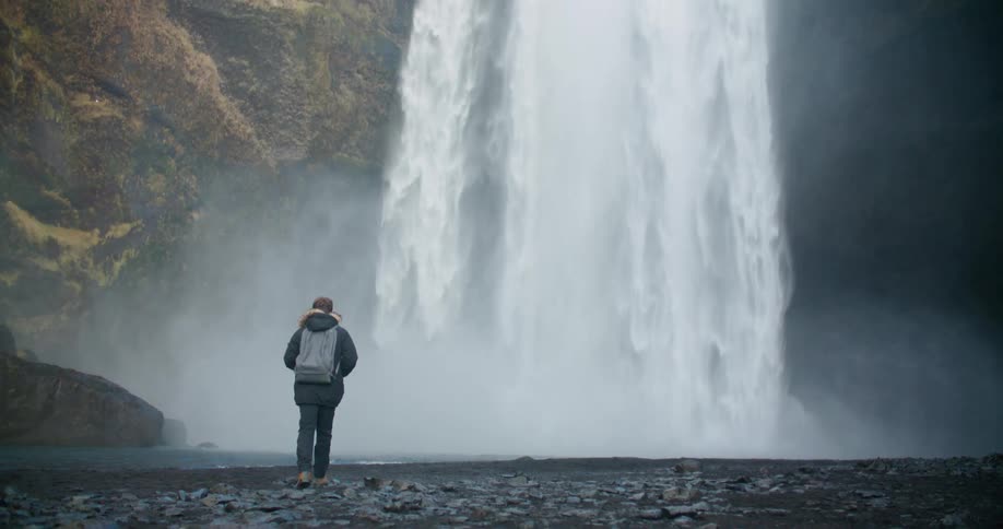 A man is walking towards a waterfall in spring