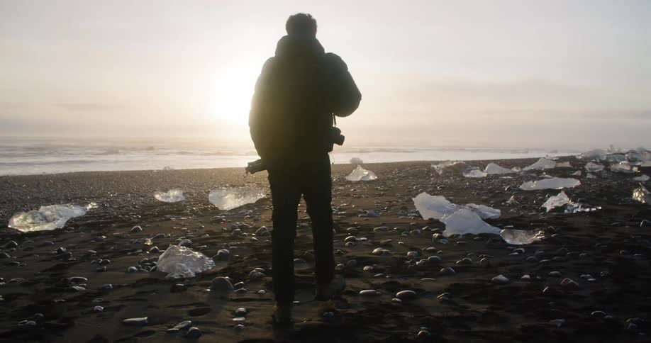 A man is walking on the beach coast in winter at dusk
