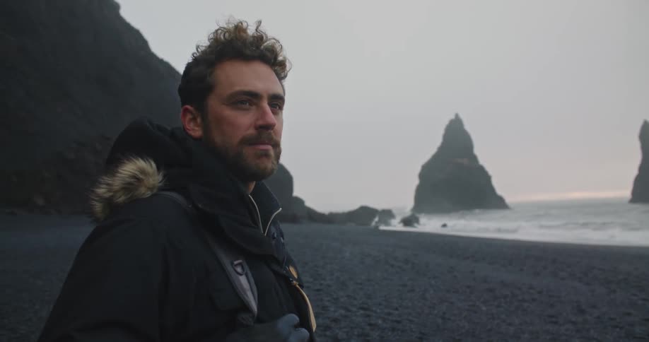 Young man standing on the reynisfjara black sand beach at sunset