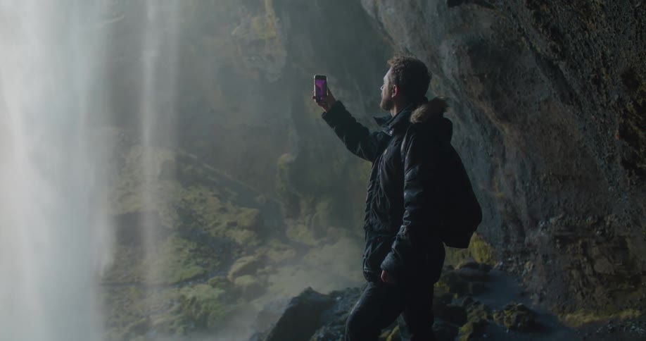 A man is taking pictures of a waterfall