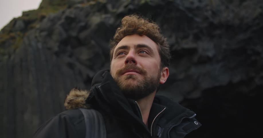 A man stands by the cave on a windy day