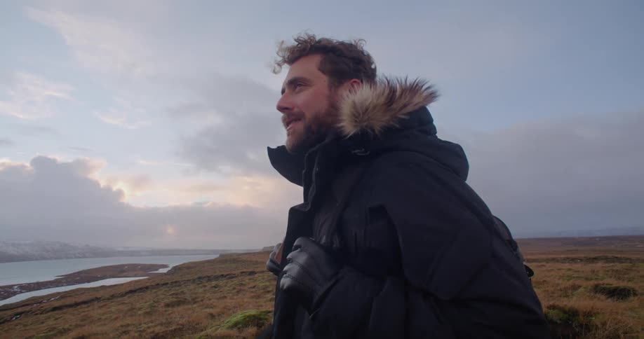 A man is smiling and standing on the coast of a beach