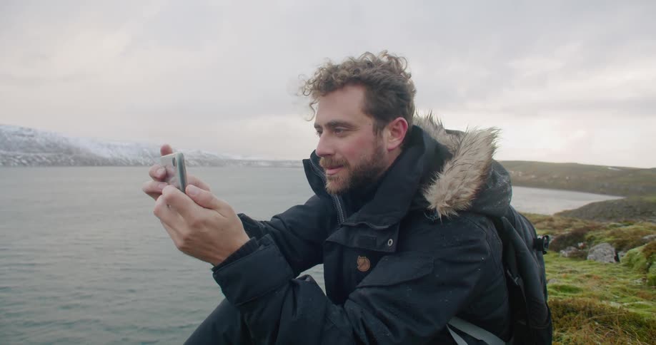 A man is sitting on the coast and taking pictures of the horizon