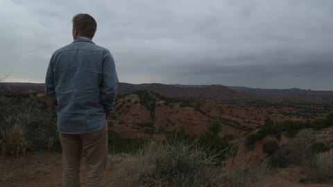 A man walking through the desert on a cloudy night