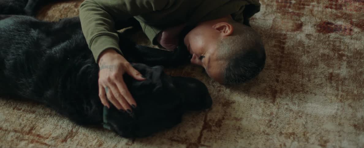 Woman lies on floor with dog petting canine on its head