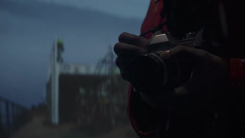 Person wearing a red jacket takes pictures with a vintage film camera outdoors