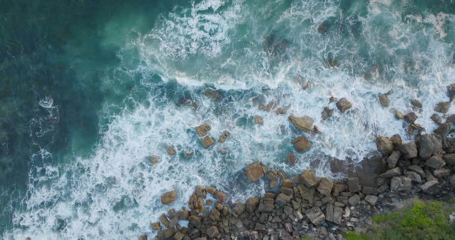 Aerial view of ocean waves crashing towards the coast