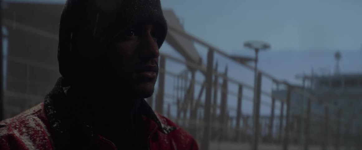 A man is standing in the rain next to a building taking photographs