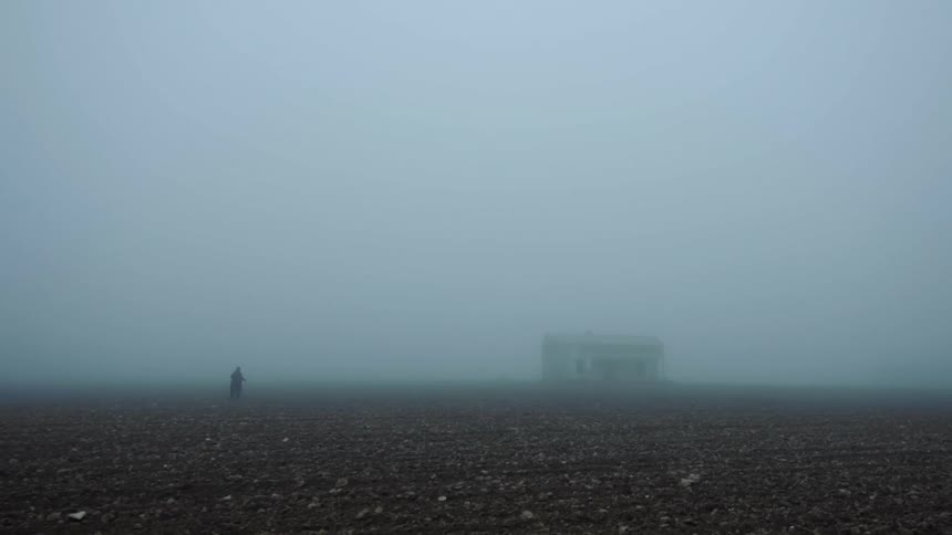 A person is running through a field in the fog