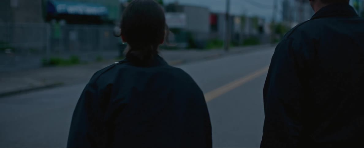 Two pedestrians are walking in the middle of a road in a city