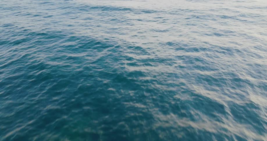 Aerial view of the calm surface of the clear ocean waters reaching the horizon