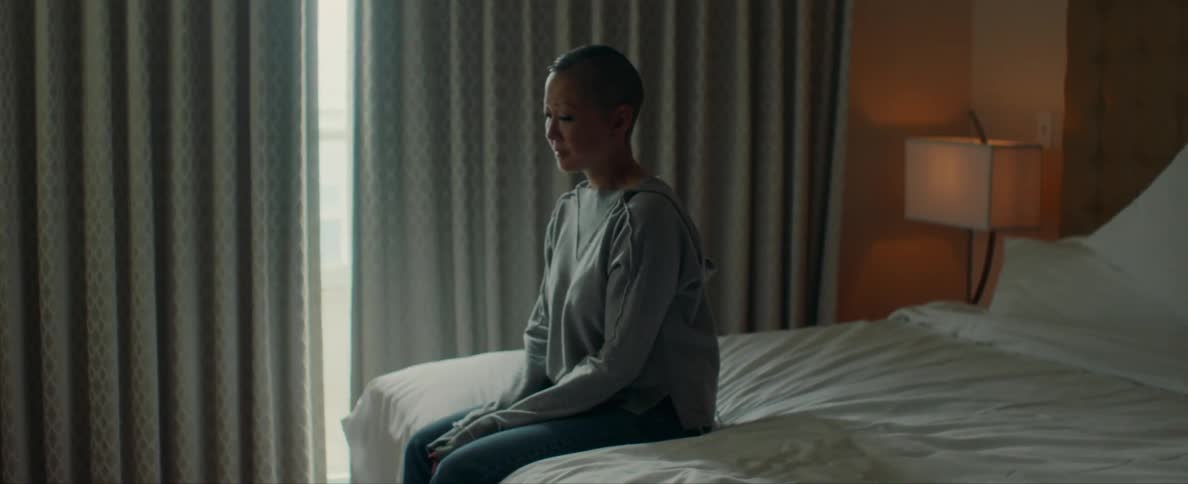 Sad asian woman sitting on a bed with curtains closed