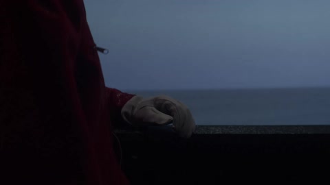 A person is looking in his backpack near the ocean