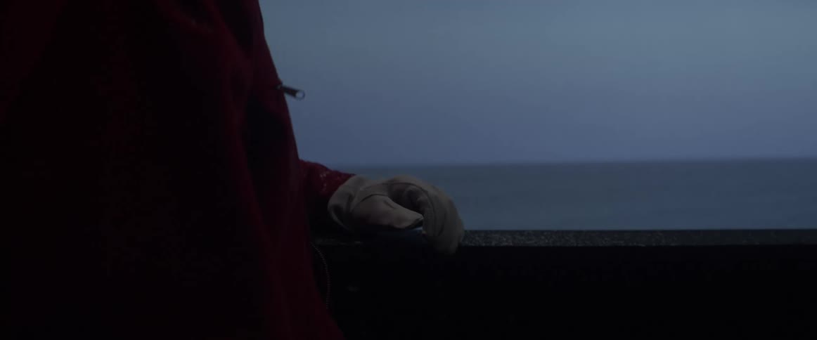A person is looking in his backpack near the ocean