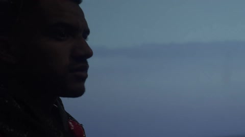 Person wearing a red jacket takes pictures with a vintage film camera outdoors close to the ocean