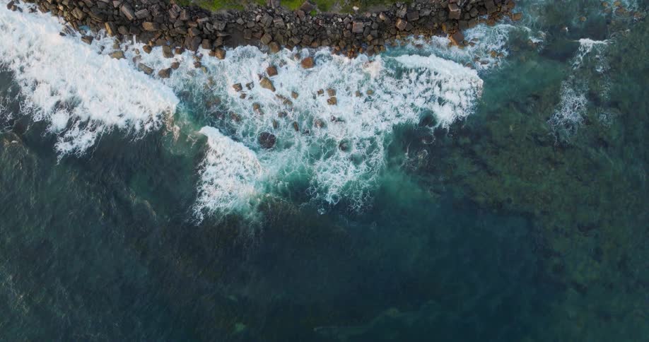 Ocean waves roll into a rocky coastline during the day