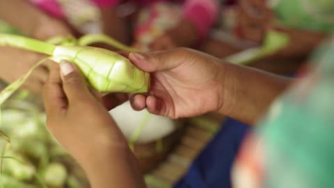 A person weaves a box out of leaves