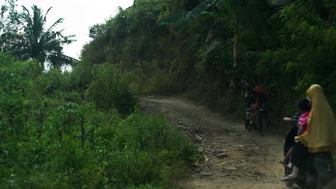 People on motorcycles drive up a dirt road
