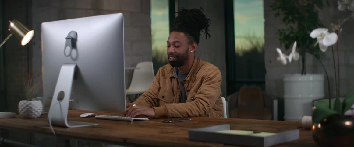 A man is sitting in an office and typing on a laptop