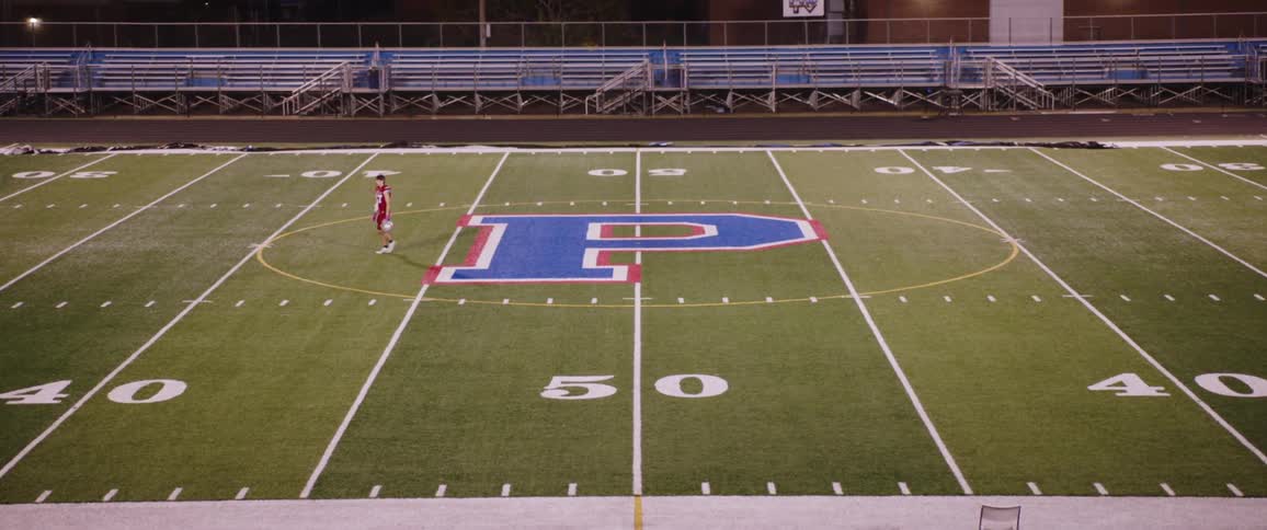 A player is walking off a football field at night