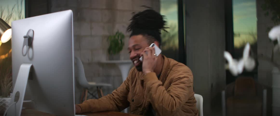 A person is sitting in their office and talking on a cellphone