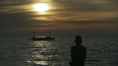 A person fishes near sunset
