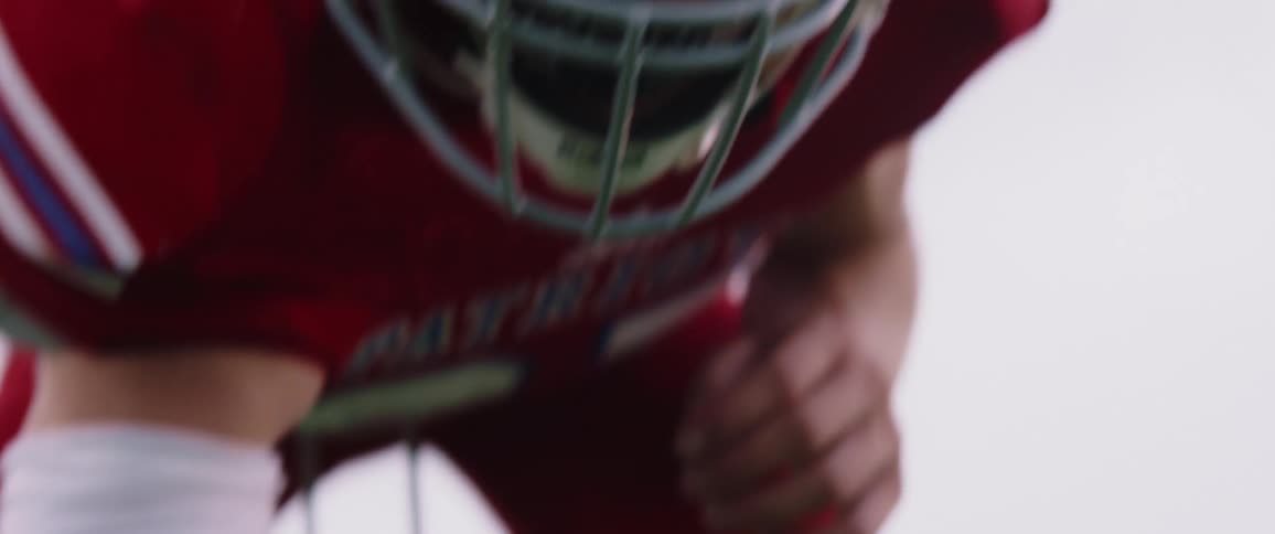 A football player leans down to touch the stadium grass